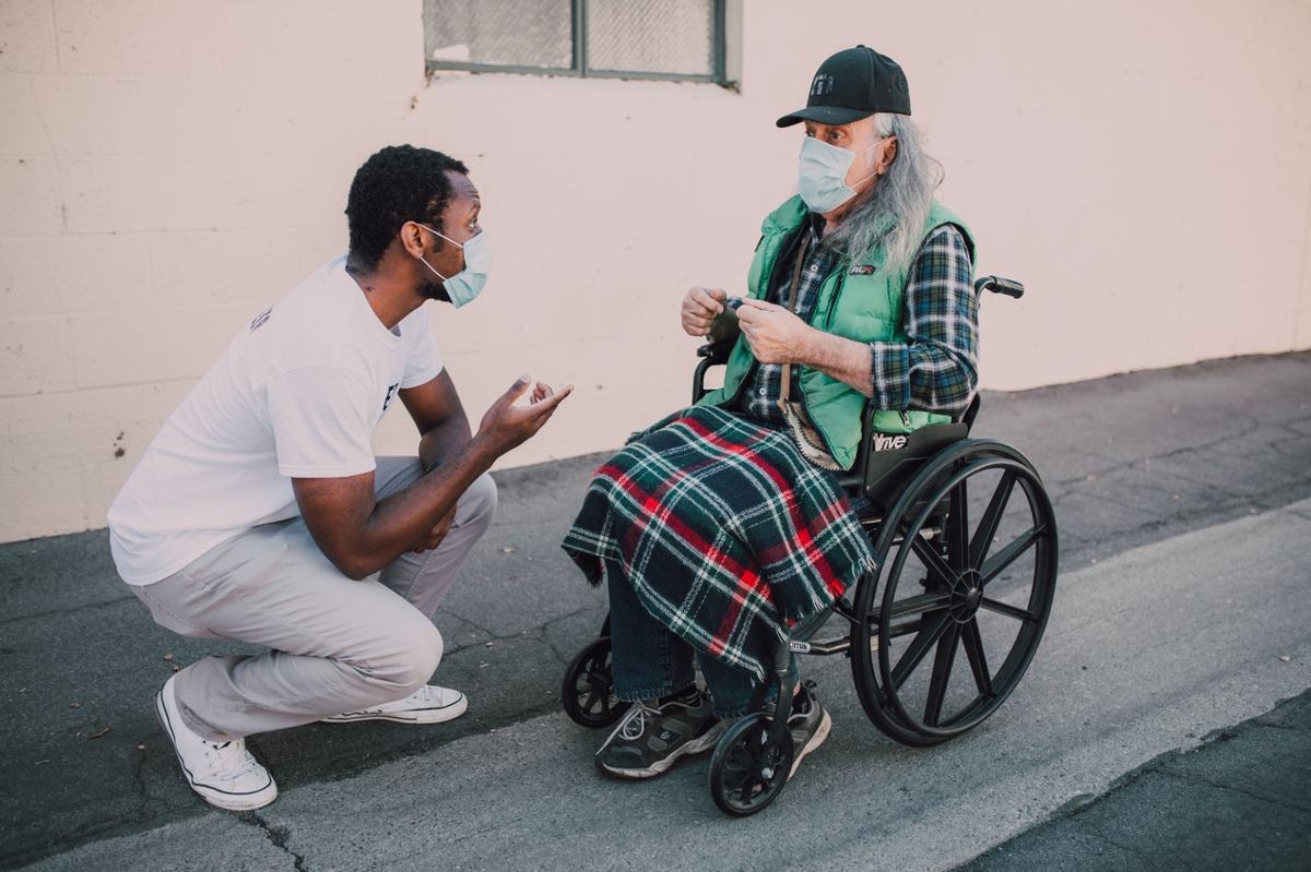 Support worker talking with an elderly man in a wheelchair
